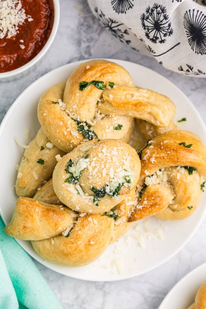 plate full of garlic knots sprinkled with parmesan cheese.