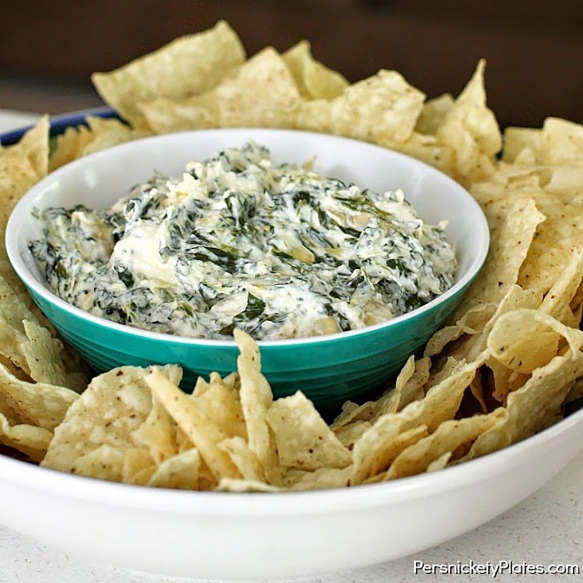 bowl of spinach artichoke dip surrounded by tortilla chips