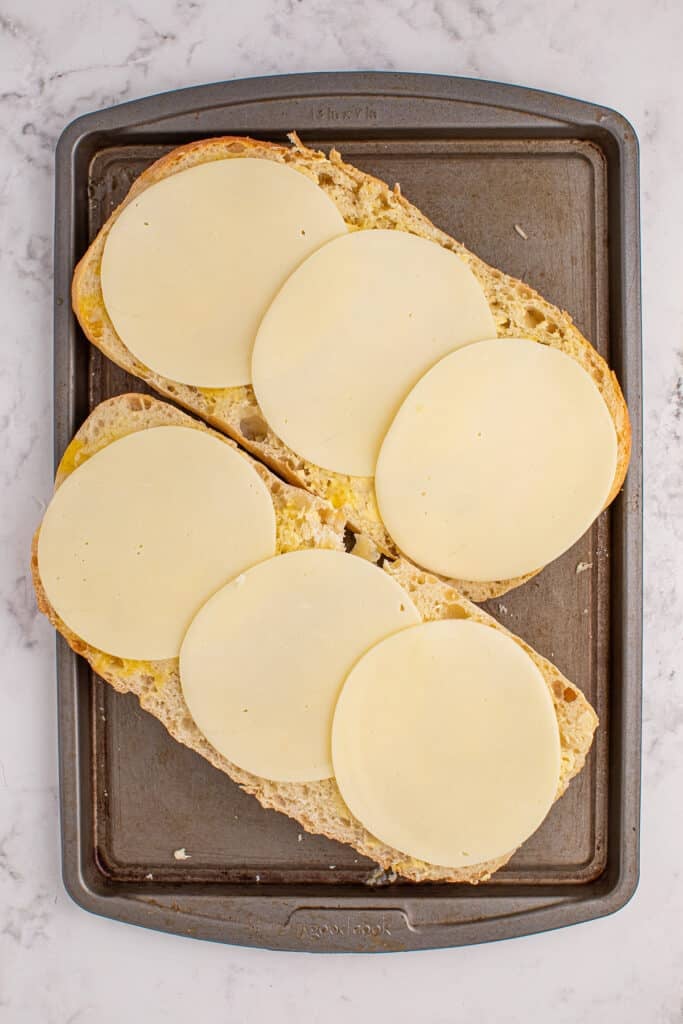 overhead shot of sliced loaf of bread piled with provolone circles.