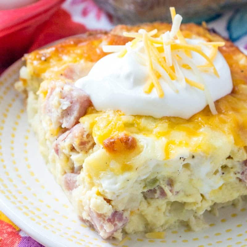 close up on ham & potato casserole on plate topped with sour cream