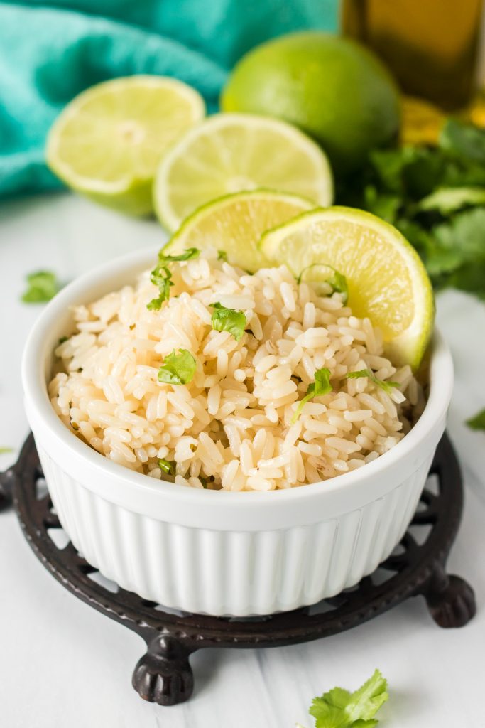 bowl of rice topped with cilantro and garnished with lime wedges.