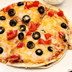 mexican pizza topped with black olives on a white plate