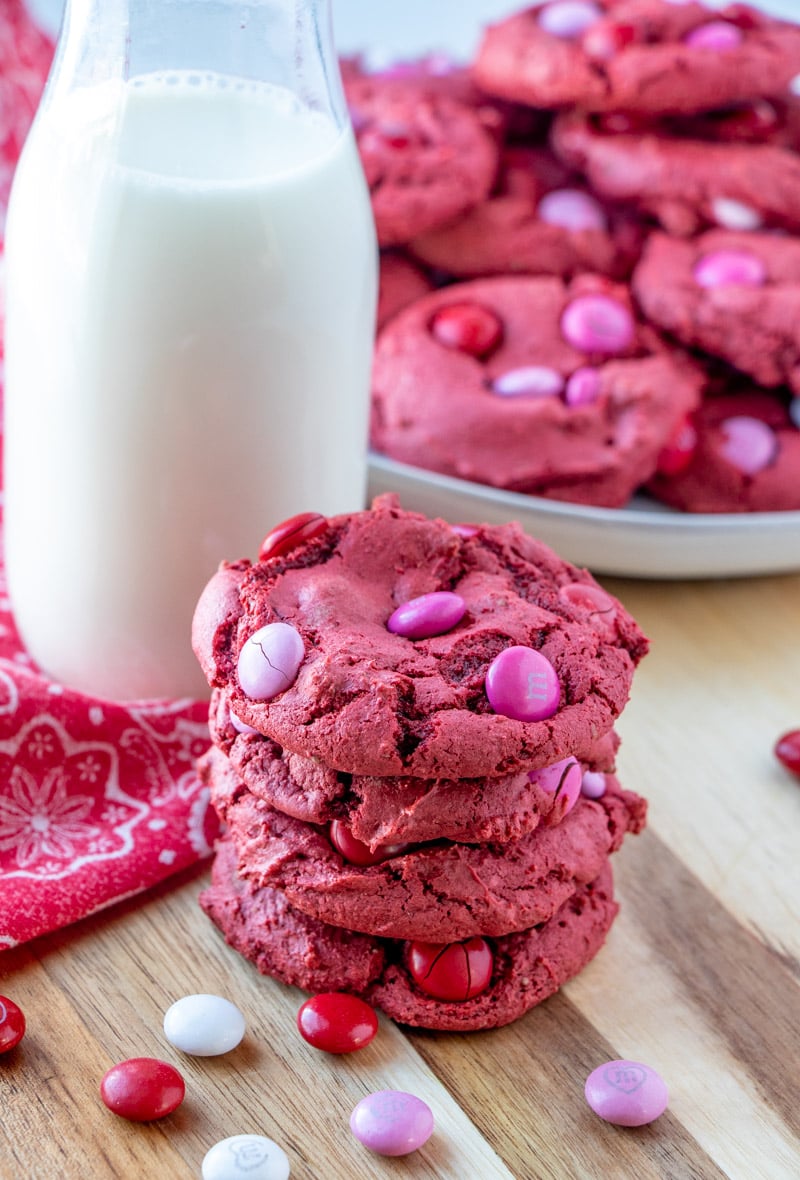 stack of red velvet cookies next to a jar of milk