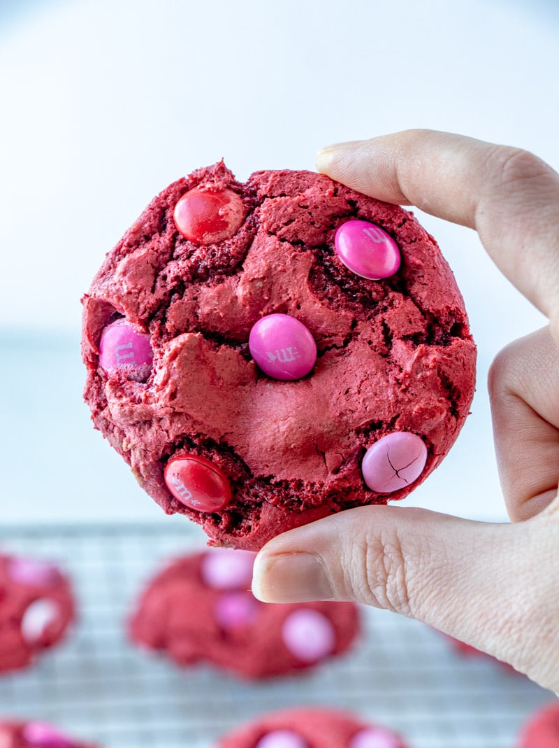hand holding a red velvet cookie with M&Ms
