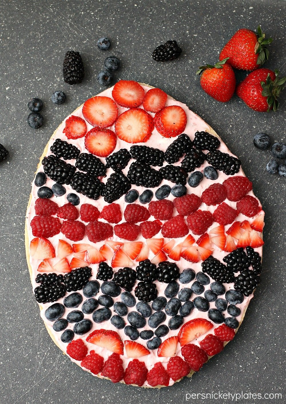 A sugar cookie base with a strawberry cream cheese frosting topped with fresh berries makes the perfect Easter Egg Fruit Pizza. Fun to decorate with the kids! | www.persnicketyplates.com