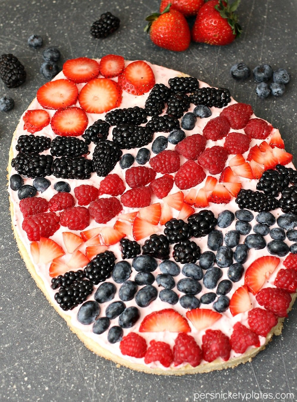 A sugar cookie base with a strawberry cream cheese frosting topped with fresh berries makes the perfect Easter Egg Fruit Pizza. Fun to decorate with the kids! | www.persnicketyplates.com