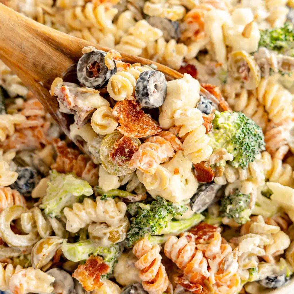 wooden spoon lifting a scoop of bacon ranch pasta salad.