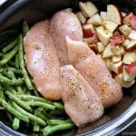 overhead shot of raw chicken in a crockpot with green beans and potatoes.