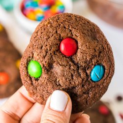 hand holding a brownie M&M cookie.