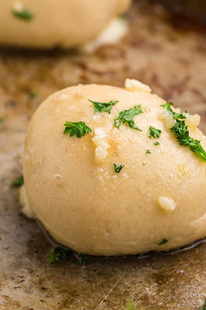 closeup shot of a roll topped with parsley & garlic.