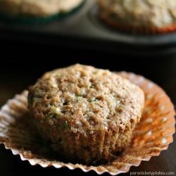 apple zucchini muffin sitting on a peeled cupcake wrapper.