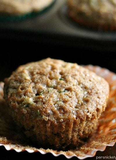 apple zucchini muffin sitting on a peeled cupcake wrapper.
