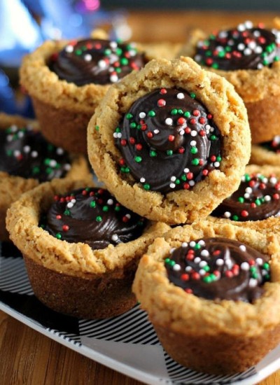 stack of peanut butter cookie cups filled with chocolate & topped with christmas sprinkles