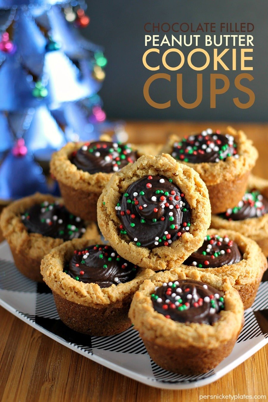 stack of peanut butter cookie cups filled with chocolate ganache & topped with christmas sprinkles