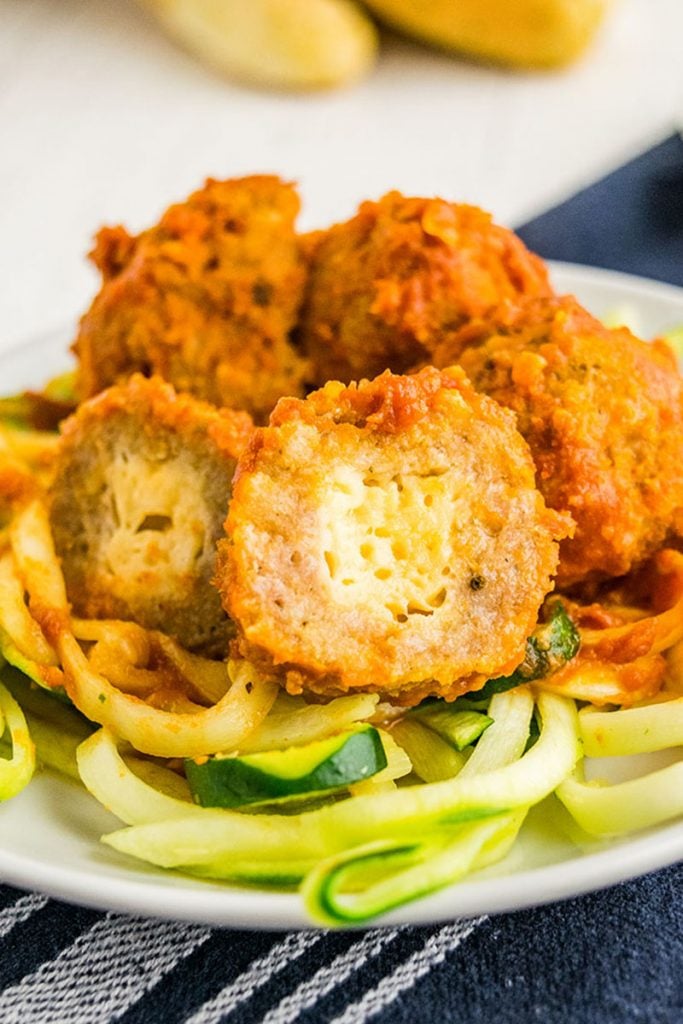 a turkey meatball sliced open with mozzarella inside on a bed of zoodles