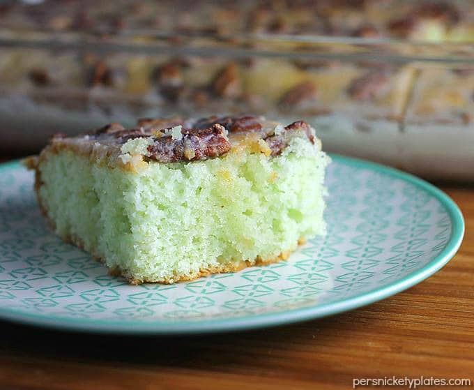 Pistachio Cake starts with a cake mix so it’s super easy and always a crowd pleaser. I’ve never made this cake without being asked for the recipe! Topped with pecans and filled with delicious pistachio pudding, this pistachio pudding cake is simple yet irresistible! | www.persnicketyplates.com