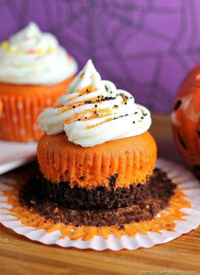 Brownie Bottom Halloween Cupcakes have a layer of dark chocolate brownie topped with orange cake batter and finished off with buttercream and sprinkles. They are the perfect mix of semi-homemade and "from scratch" to be easy but really fun and festive for your next Halloween party! | Persnickety Plates