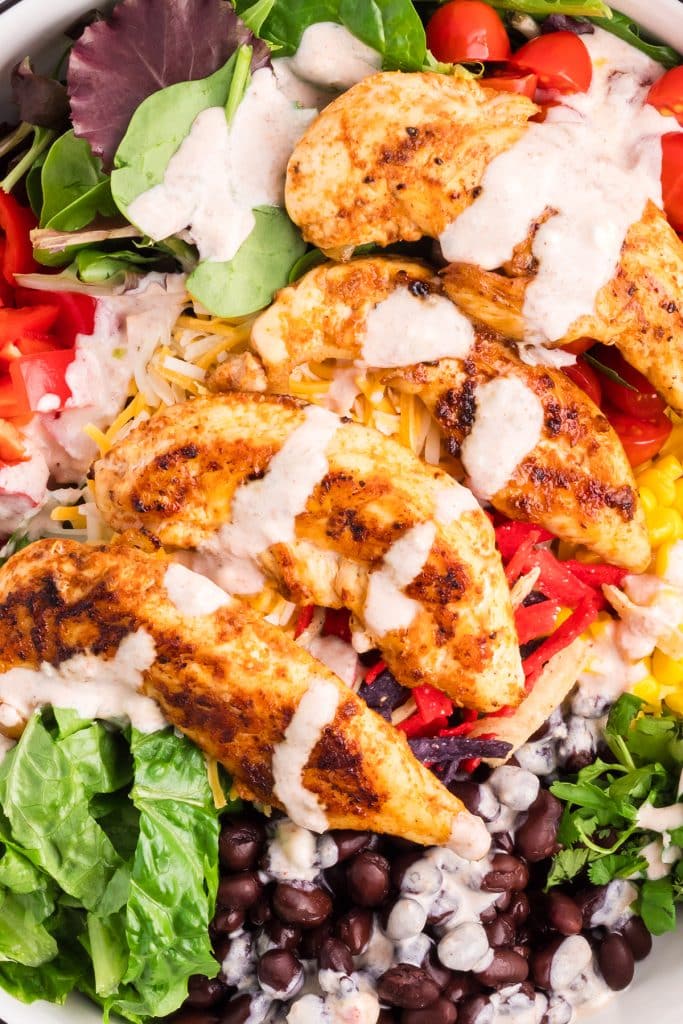 dressing drizzled over chicken in a southwest salad.