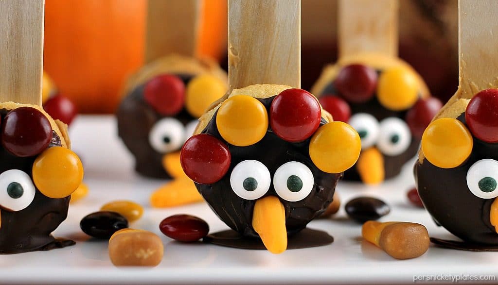 Nilla Wafer Thanksgiving Turkeys are cookies sandwiched together with peanut butter, dipped in chocolate, and decorated with fall colored M&Ms, candy corn, and candy eyes, all on a popsicle stick! So fun for the kids and festive for the Thanksgiving table!