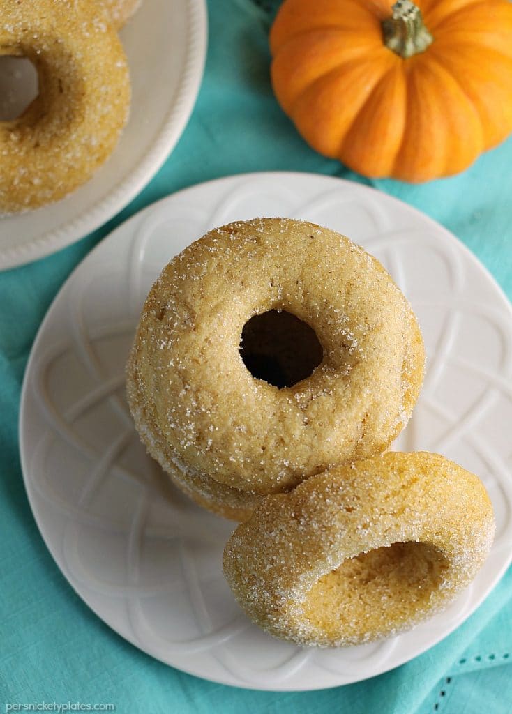 overhead shot of donuts on a white plate with small pumpkin in corner