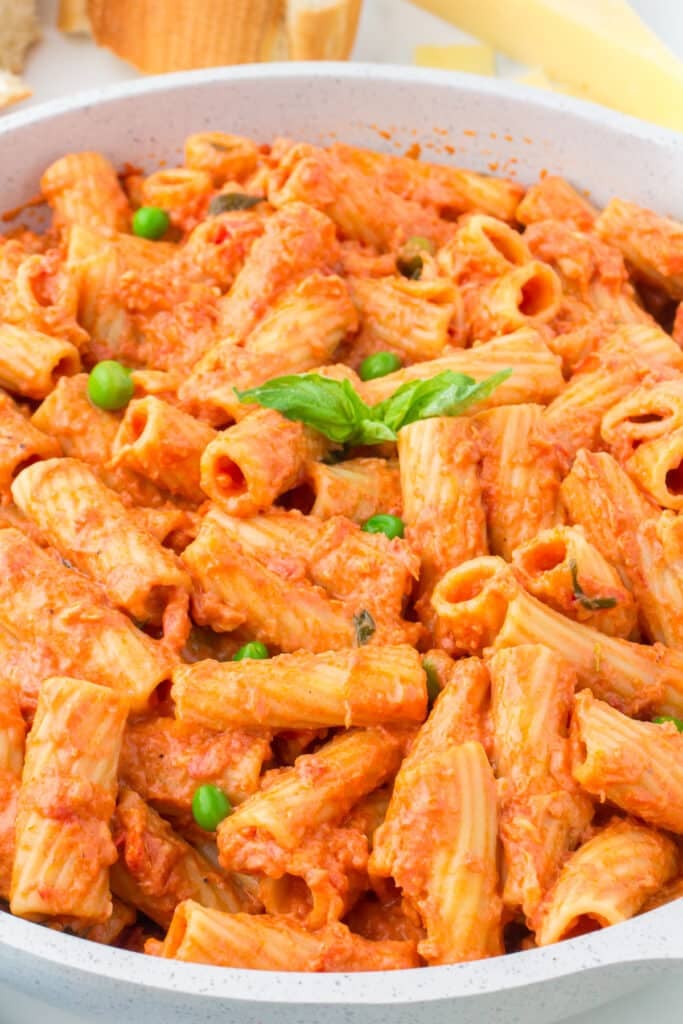 large bowl of vodka rigatoni with green peas.