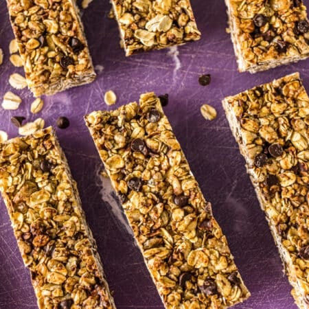 closeup of homemade granola bars sliced on a purple cutting board.