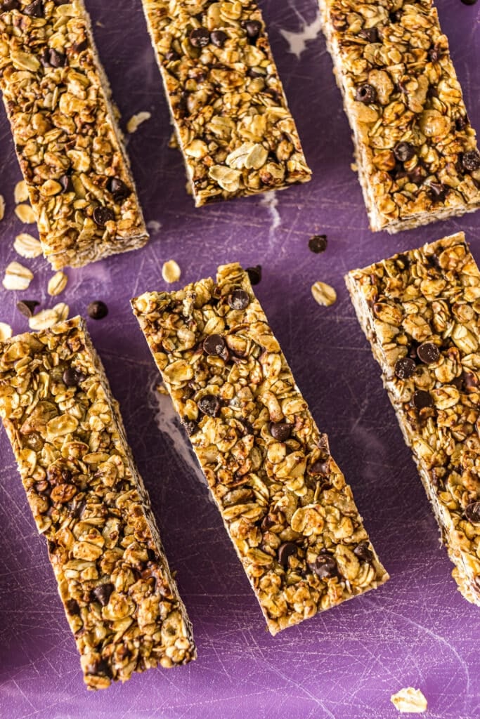 closeup of homemade granola bars sliced on a purple cutting board.