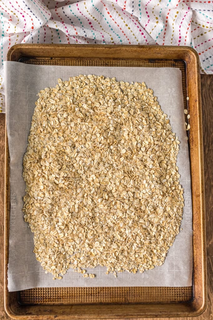 overhead shot of rolled oats on a baking sheet lined with parchment paper.