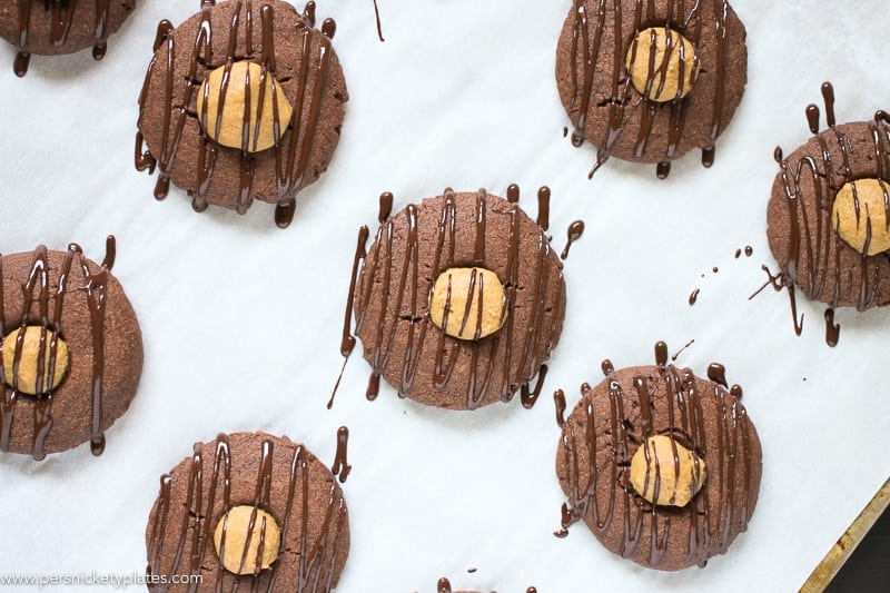cookie sheet with many chocolate cookies filled with peanut butter centers and drizzled with melted chocolate