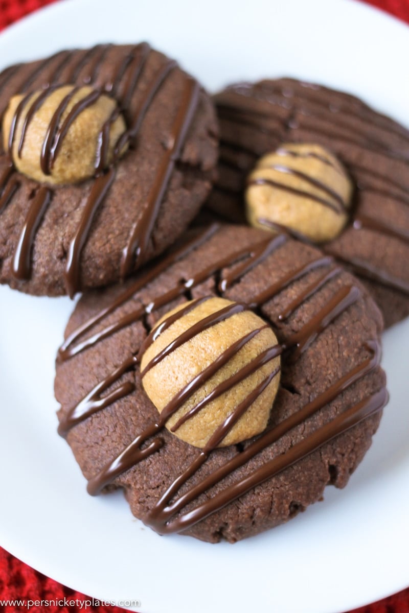close up of plate of chocolate cookies filled with peanut butter centers and drizzled with melted chocolate