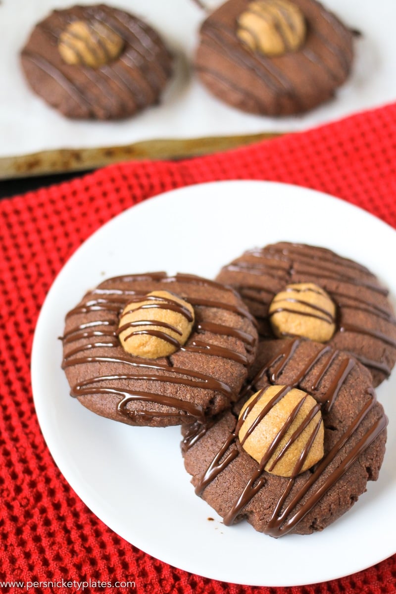 Plate of three chocolate cookies filled with peanut butter and drizzled with chocolate on a red napkin