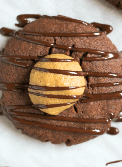 close up of chocolate cookie filled with peanut butter and drizzled with chocolate