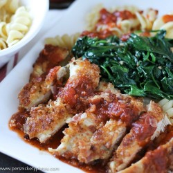 breaded chicken on white plate with marinara and spinach