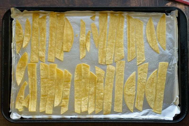 sliced corn tortillas on a baking sheet for tortilla strips