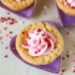 Valentine Sugar Cookie Cups are a simple, semi-homemade treat that you can whip up in no time! A sugar cookie base filled with pink frosting and topped with Valentine sprinkles. | www.persnicketyplates.com
