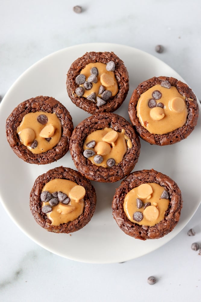 five brownie bites topped with peanut butter on a white plate