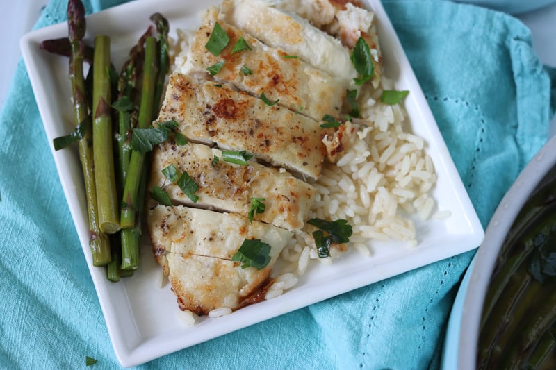 white plate of sliced chicken breast asparagus and rice
