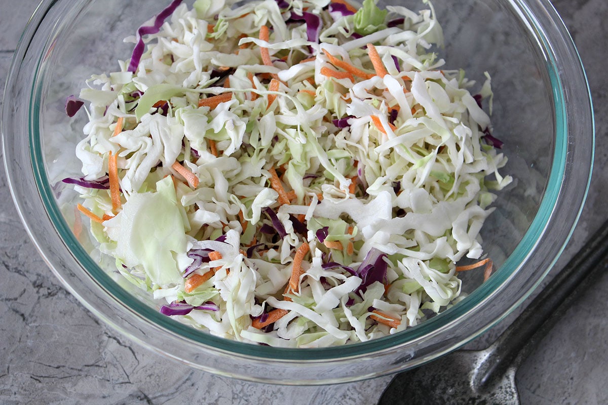 shredded cabbage, carrots, and red cabbage in glass bowl