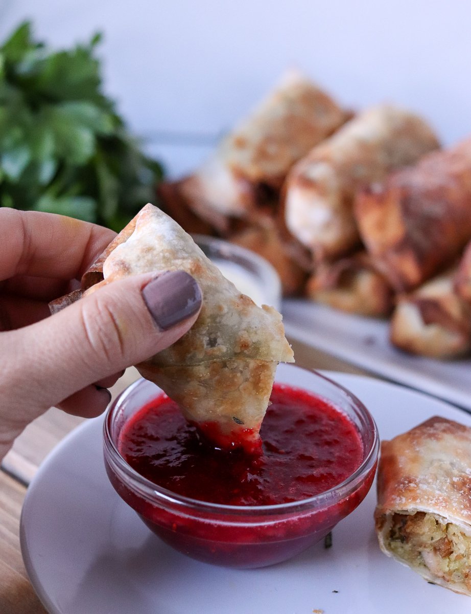 air fryer egg roll being dipped into cranberry sauce