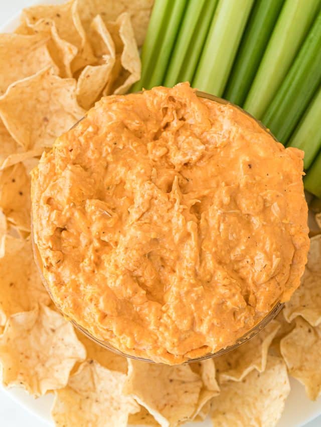 overhead shot of buffalo chicken dip on a platter with chips & celery