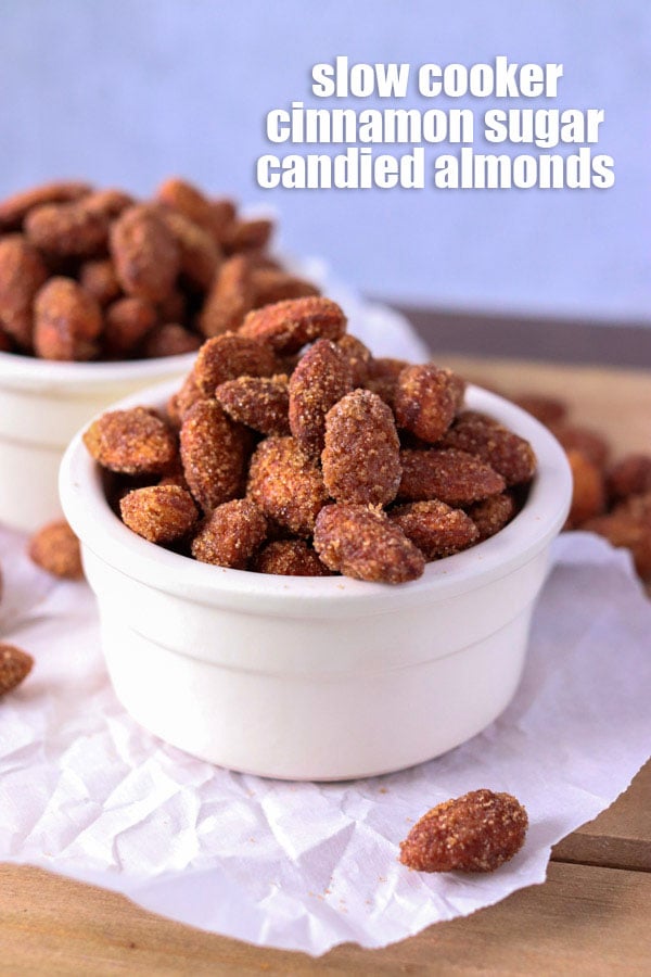 two bowls of candied almonds in white bowls on parchment paper