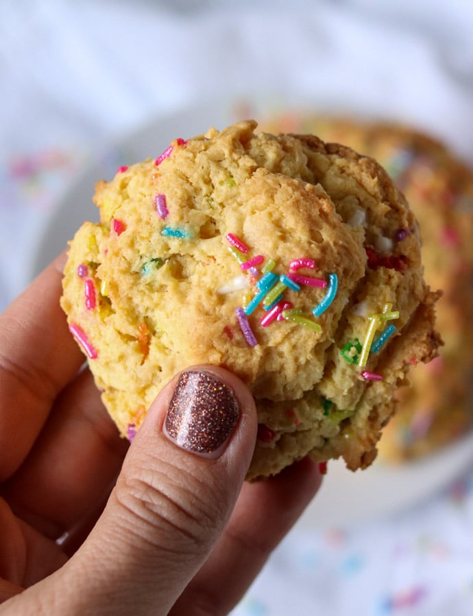 hand holding a cream cheese sprinkle cookie with rainbow sprinkles