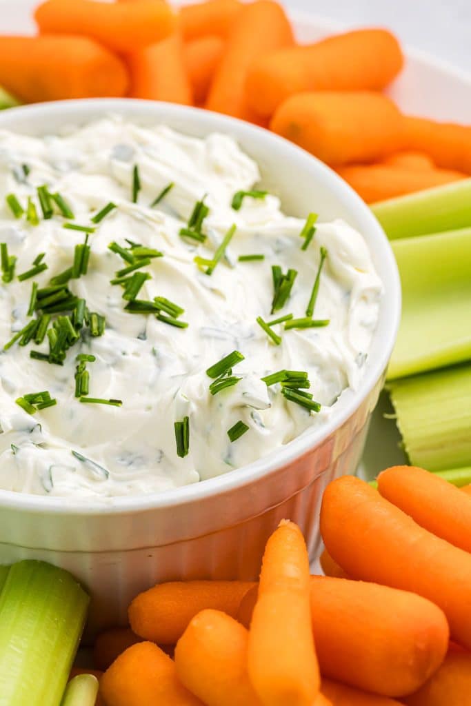 creamy garlic herb dip surrounded by carrots & celery sticks.