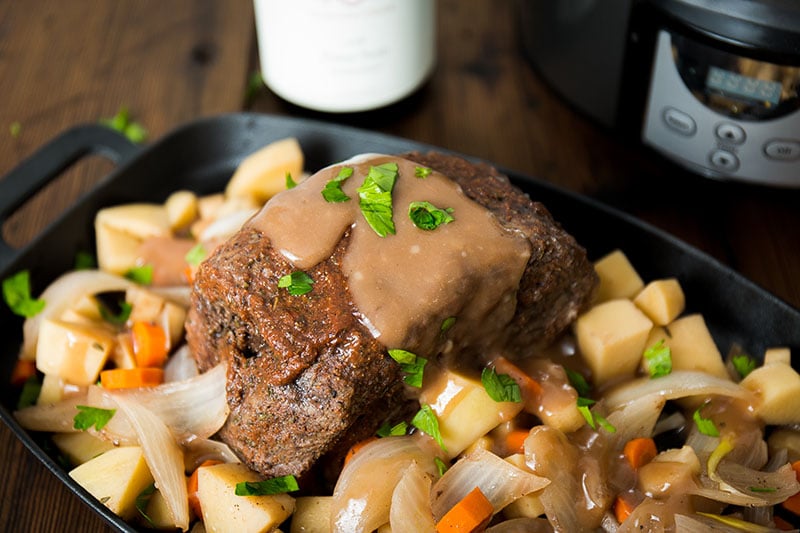 pot roast topped with gravy over vegetables