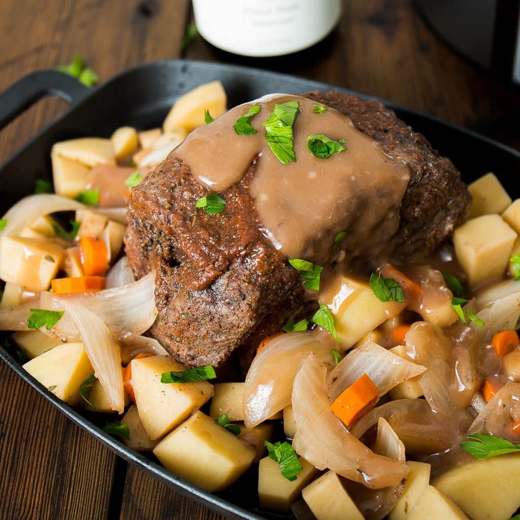 platter of pot roast with potatoes, carrots, and onions.