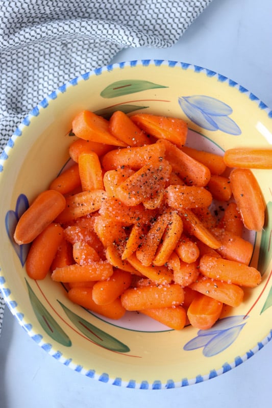 overhead shot of carrots in a bowl with seasoning