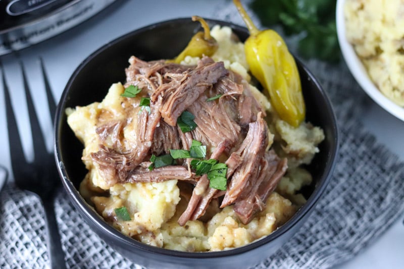 bowl of pot roast on top of mashed potatoes with pepperonicinis