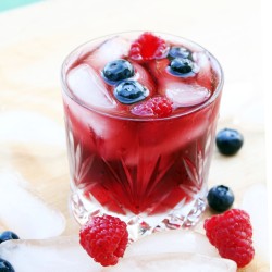 glass of sangria topped with blueberries & raspberries