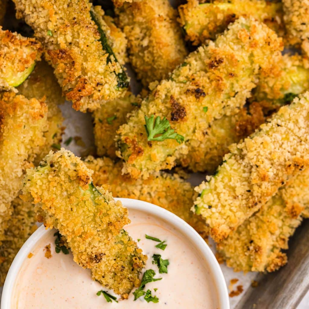 crispy panko crusted zucchini fries dipping in spicy ranch sauce.
