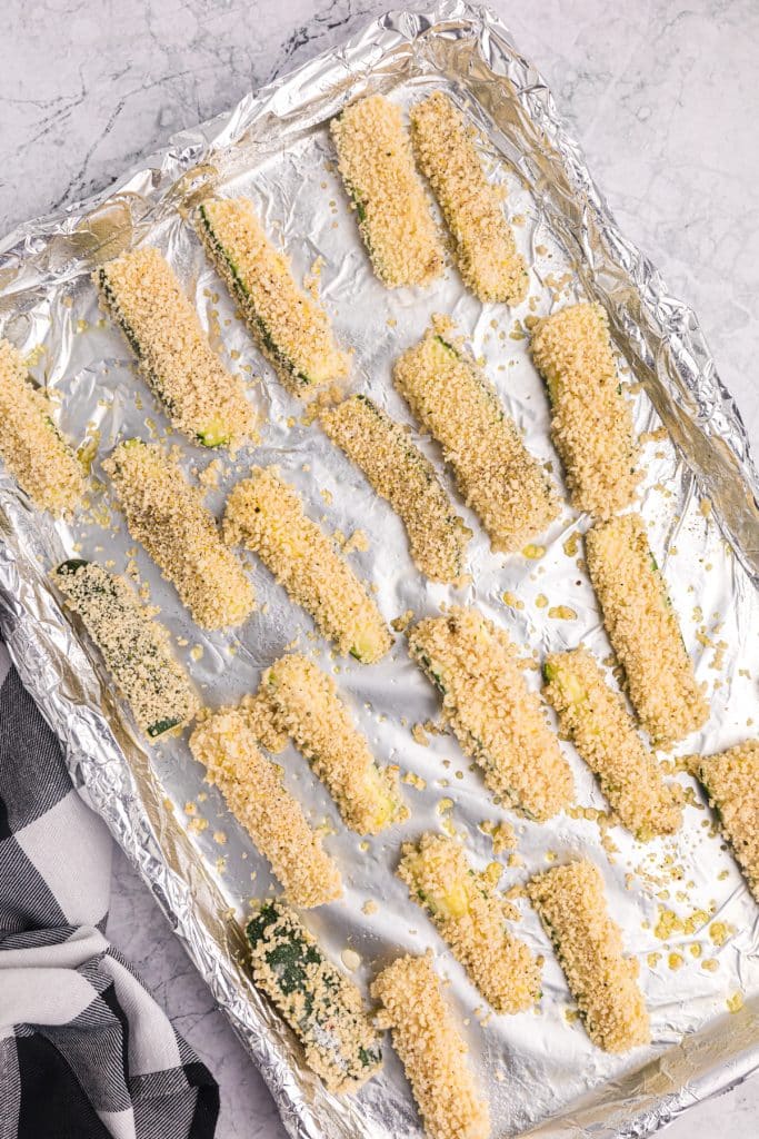 panko crusted zucchini fries on a foil wrapped baking sheet.